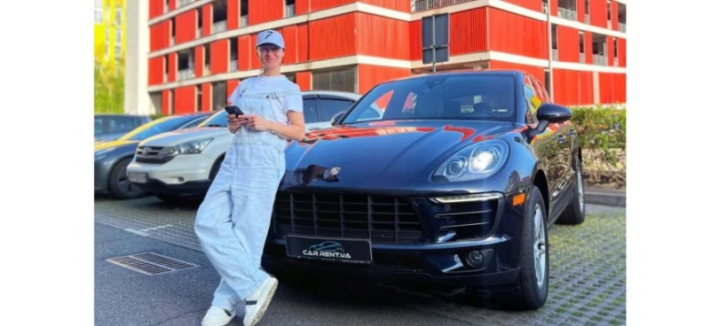 Жінка стоїть поруч із чорним автомобілем у Києві