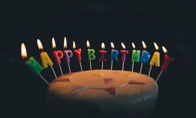 Торт із свічками у формі літер, що пишуть «Happy Birthday».