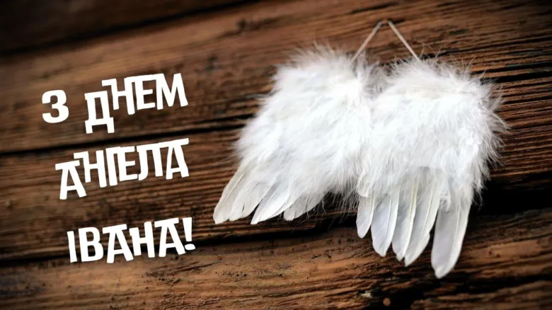 Білі крила ангела на дерев'яному фоні з привітанням.