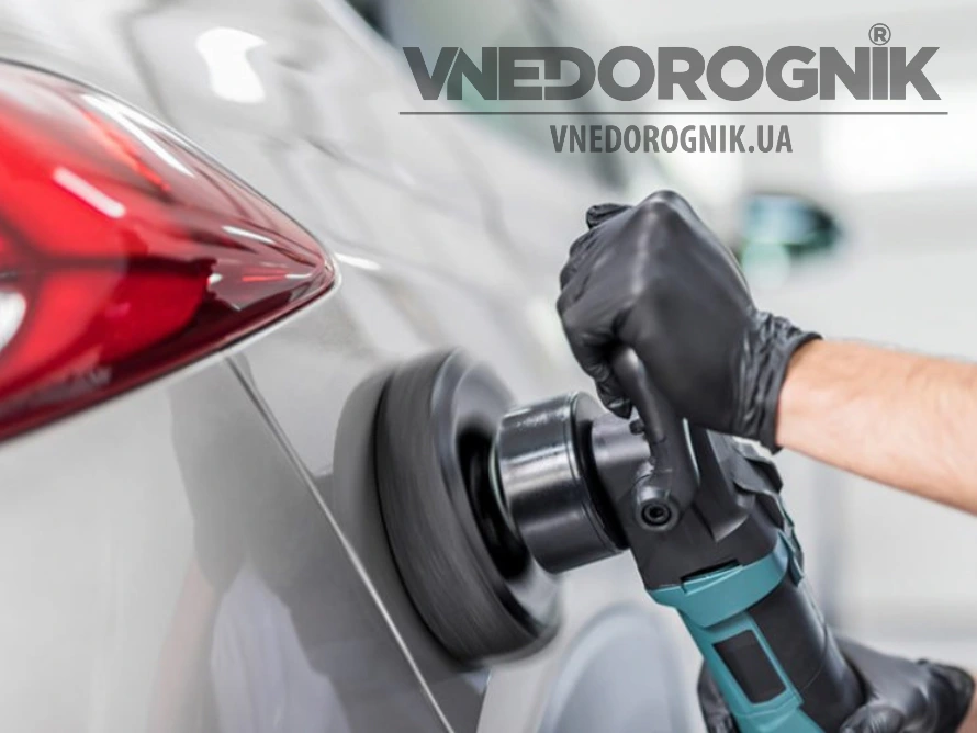 Людина полірує білий автомобіль напівпрофесійним інструментом.