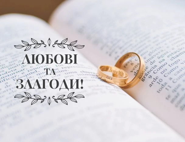 Золоті обручальні кільця на відкритій книзі з привітанням про любов і мир.