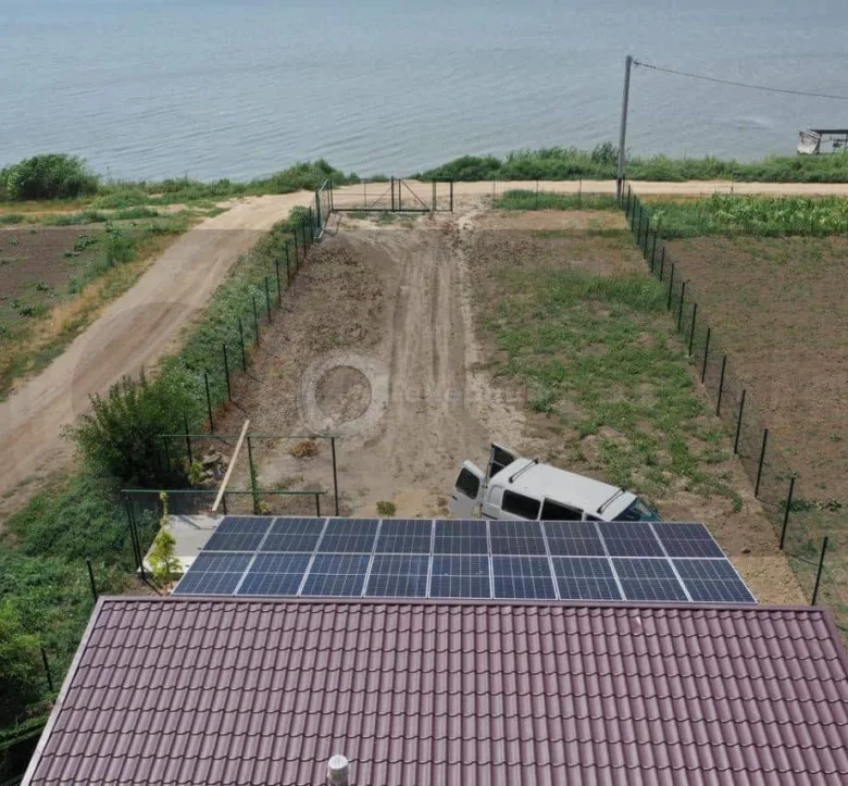 Сонячні панелі на даху біля водойми для статті про автономні сонячні електростанції